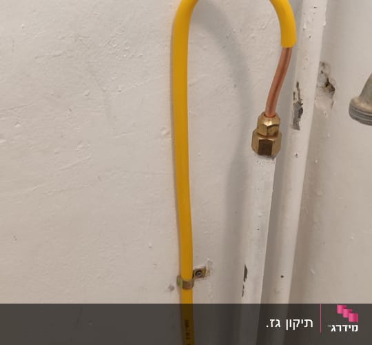 צינור גז צהוב מחובר לקיר לבן